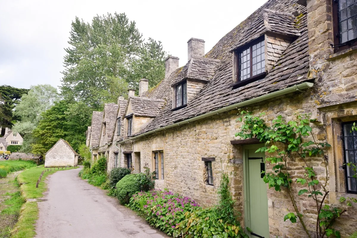Cotswolds honey-stone village with thatched cottages and gardens